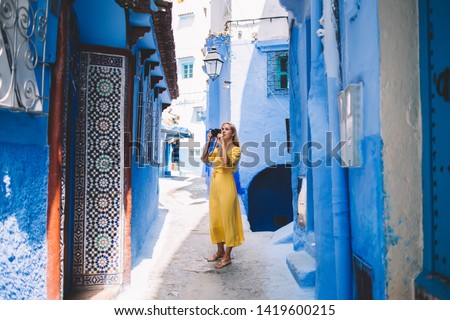 Good looking female with professional camera making fotos in colorful city - Morocco testing new equipment, woman photographer taking pictures of old streets around unesco heritage during vacations