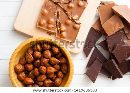 broken chocolate and hazelnuts on white wooden table