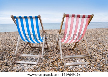 Deckchairs on beach, typical english seaside holiday scene, red and blue stripes representing main political party of labour or conservative