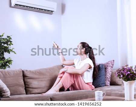 woman using remote control of airconditioner
