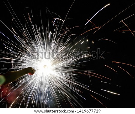hand charki, a hand firework emitting circular sparks in black background