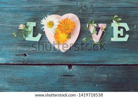Love word of wooden letters and flowers on the table, top view, congratulation concept