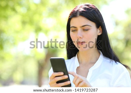 Serious beauty woman using smart phone standing in a park