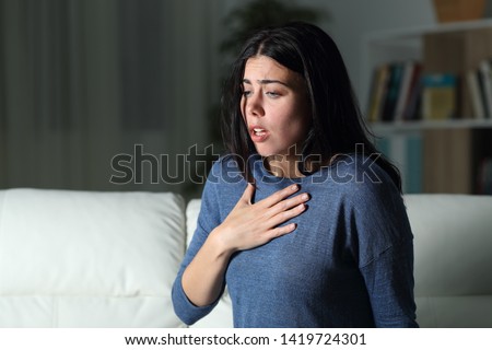Woman suffering an anxiety attack alone in the night on a couch at home Royalty-Free Stock Photo #1419724301