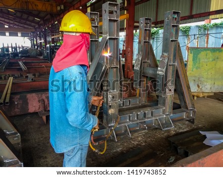 Workers are using heating torch to burn iron that is curled after welding.