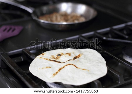 Flour tortilla cooking directly over the flame on a natural gas stove oven.
