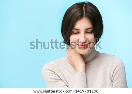 portrait of a beautiful young caucasian woman, happy and smiling, eyes closed, isolated on blue background