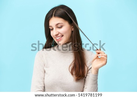 portrait of a beautiful young caucasian woman, happy and smiling, looking down, isolated on blue background