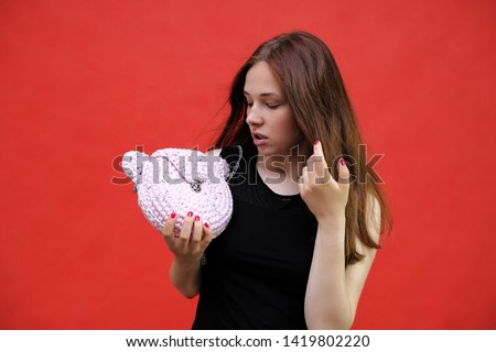 Photo portrait of a beautiful young pretty girl with dark red hair on a red background in a black jacket. Standing right in front of the camera in different poses, smiling, talking. Made in a studio.