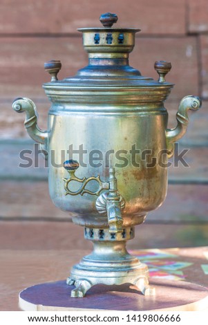 Wood-burning samovar, bowls with jam, glass of tea in glass-holder, bagels and fresh wild in the garden. Russian tea time concept; Vertical picture