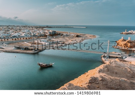 Beautiful view on the Oman city - Sur, bridge over the turquoise sea, big ship, white town buildings on the coast. Royalty-Free Stock Photo #1419806981