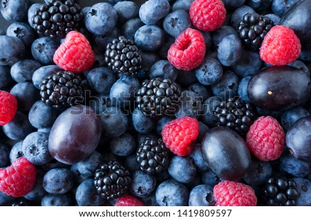 Background of fresh fruits and berries. Ripe blackberries, blueberries, plums, raspberries. Mix berries and fruits. Top view. Background berries and fruits. Black-blue and red food. Royalty-Free Stock Photo #1419809597