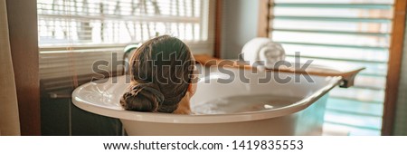 Luxury bath woman relaxing in hot bathtub in hotel resort suite room enjoying pampering spa moment lifestyle banner panorama. Royalty-Free Stock Photo #1419835553
