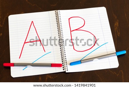 The first letters of the alphabet in the notebook. Markers.
