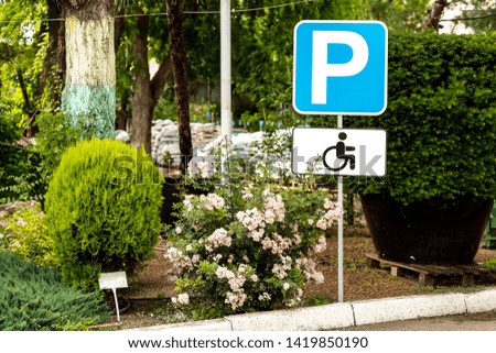 The sign is parking for disabled people at the curb, in the background is a garden with plants, nobody.