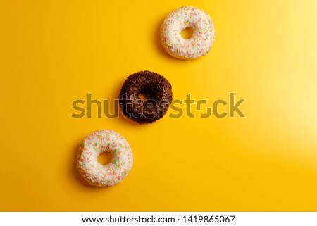 three white and black donuts on yellow background top view