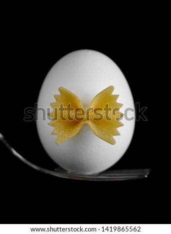 white chicken eggwhite chicken egg on a fork with a bow of pasta on a black background