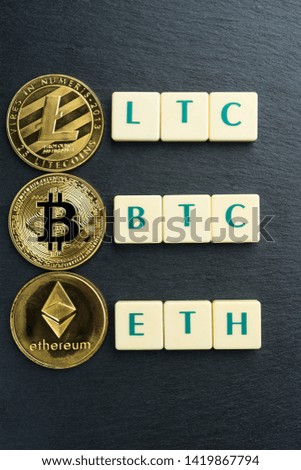 Physical Bitcoin, Litecoin and Ethereum gold coins with text made out of letter tiles. Cryptocurrency. Vertical orientation.