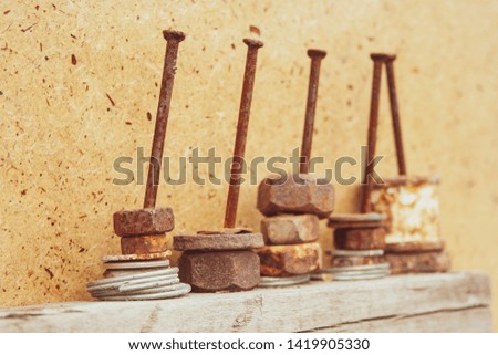Organized old rusty nuts on grunge and aged nails on wooden background. Concept of work and construction