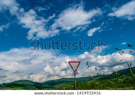 The yield sign on the road against the background of the cloudy sky