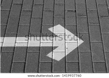 Right pointing arrow on asphalt in black and white. Signs and symbols.