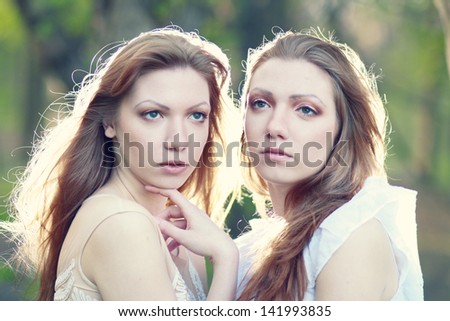 two Beautiful woman twins in the morning park focus on one of the sisters