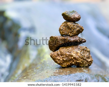 Image of four stone arrangement with water flowing through with a waterfall in the background