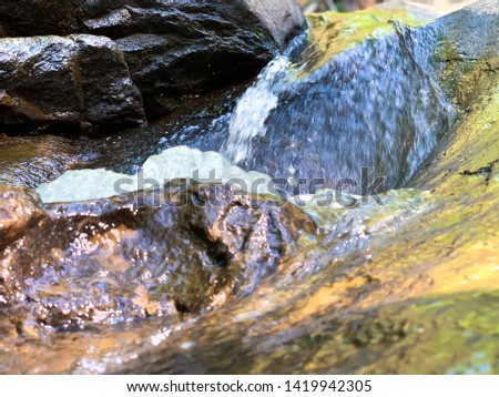 The rock image has water flowing through the rock.  There is a waterfall in the background.