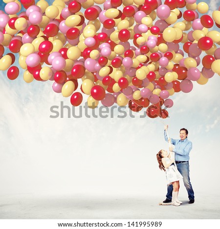 Image of father and daughter holding bunch of colorful balloons