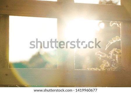 Unique photograph of the sun appearing through the square of a fence creating a really smooth and natural lens flare in great detail.