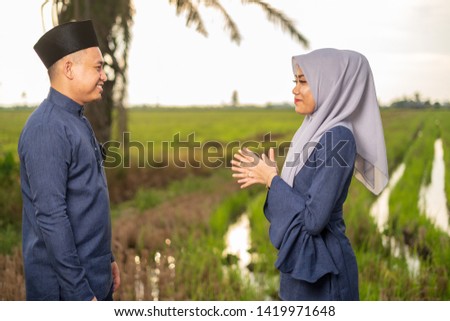 muslim friends and families visiting home and greet embrace each other celebrating eid mubarak handshaking ask for forgiveness as Asian Muslim culture during with paddy background. Selective focus.
