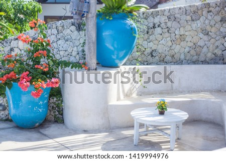 White terrace in Mediterranean style. huge blue vases, flowers, a table, a bench, sunlight and shadows on the floor
