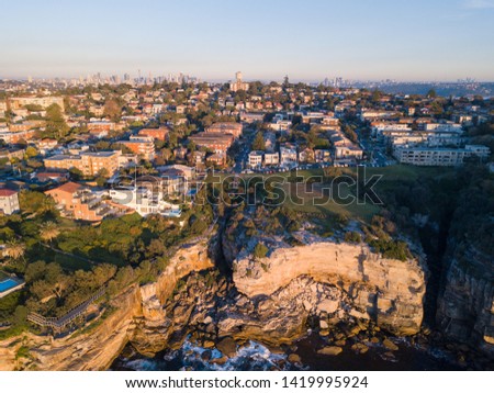 Aerial view of houses at Sydney coastline with Sydney CBD on the background.