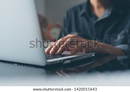 Casual business man, hipster, freelance hand typing on keyboard, working on laptop computer on desk in modern office or home office, online working concept, close up