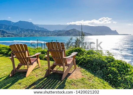lounging chairs overlooking Hanalei Bay and the Na Pali coast Princeville Kauai Hawaii USA in the late afternoon sun Royalty-Free Stock Photo #1420021202