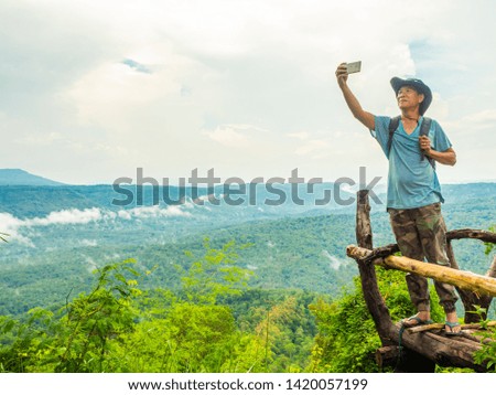 asia backpacker man take photo and selfie with mountain view and cloudy sky background copy space