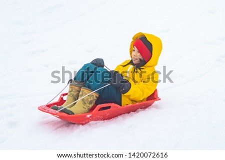 Little Japanese girl in Yellow Jacket is sliding down the snow sled in Gala Yuzawa Ski resort Niigata Tokyo Japan. For Fun and active snow playground concept