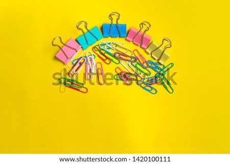 Paper clip, binder clip, colorful office supply. yellow background and empty space
