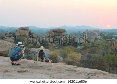 A guy photographs a girl at a sunset point in Hampi, India.