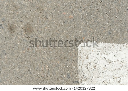 Old asphalt surface with white paint on it close up. Abstract background