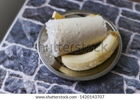 Popular South Indian steamed breakfast dish white Puttu or Pittu made of rice flour and grated coconut  in the bamboo mould with banana Kerala, India. Sri lankan food served in a plate.