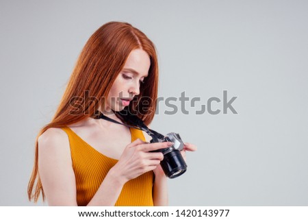 Photographer in a yellow shirt with her camera on white background studio.