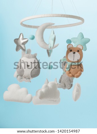 Colorful and eco-friendly children's mobile from felt for children. It consists of bear, fox, owl, rabbit, mountain, stars, clouds and balloons toys. Handmade on blue background.
