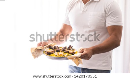 Man holding frying pan with seafood paella, rice dish. Spanish cuisine lifestyle ilarge background.Copy space.