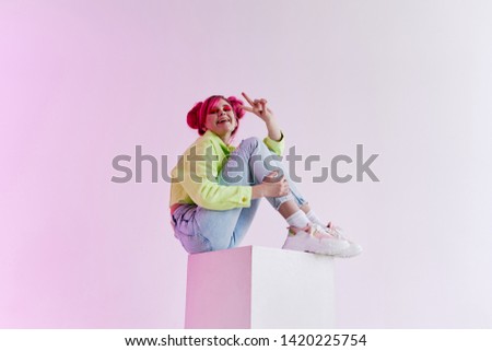 fashion style neon woman with pink hair sitting on a cube