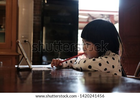 An asian girl is intend to watching the tablet.