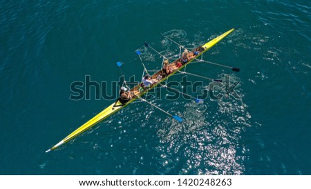 Aerial drone bird's eye view of yellow sport canoe operated by team of young women in deep blue sea waters Royalty-Free Stock Photo #1420248263
