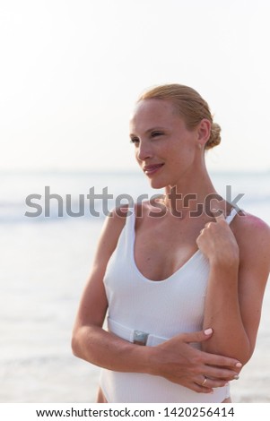 Blonde model on the beach in white sweemwear