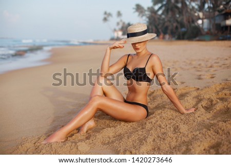 Beautiful Woman apply sun protection cream on her smooth tanned legs. Skin care. Legs on the beach. Portrait of female smearing moisturizing lotion. Sunblock concept.