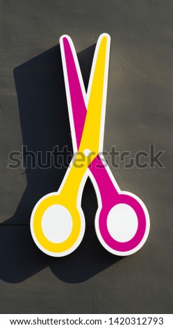 Isolated big colorful scissors sign hanging on the wall. Gdansk Wrzeszcz, Poland